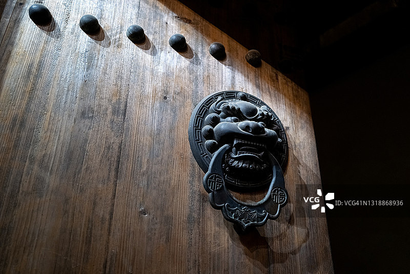 中国传统木门上的金属兽头门环，有灯光效果图片素材