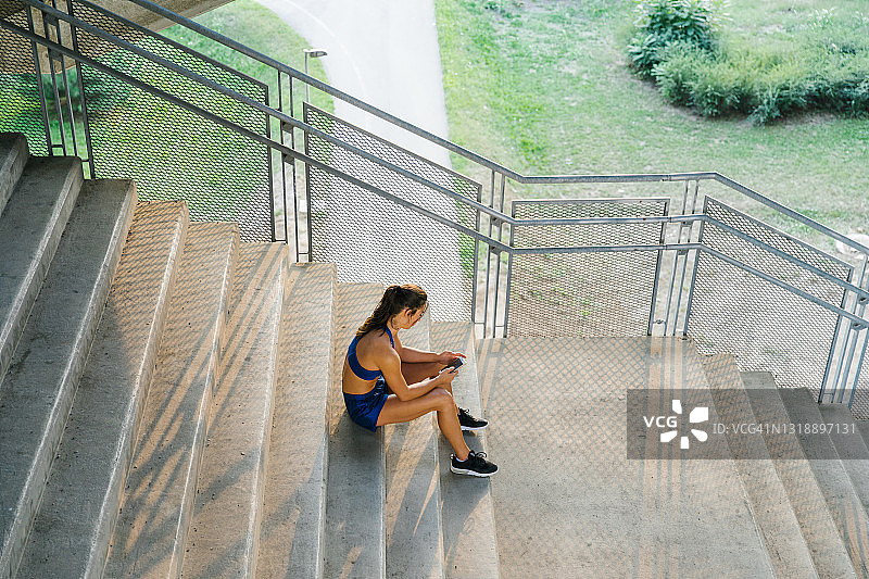 女运动员上午训练后，坐在楼梯上休息图片素材