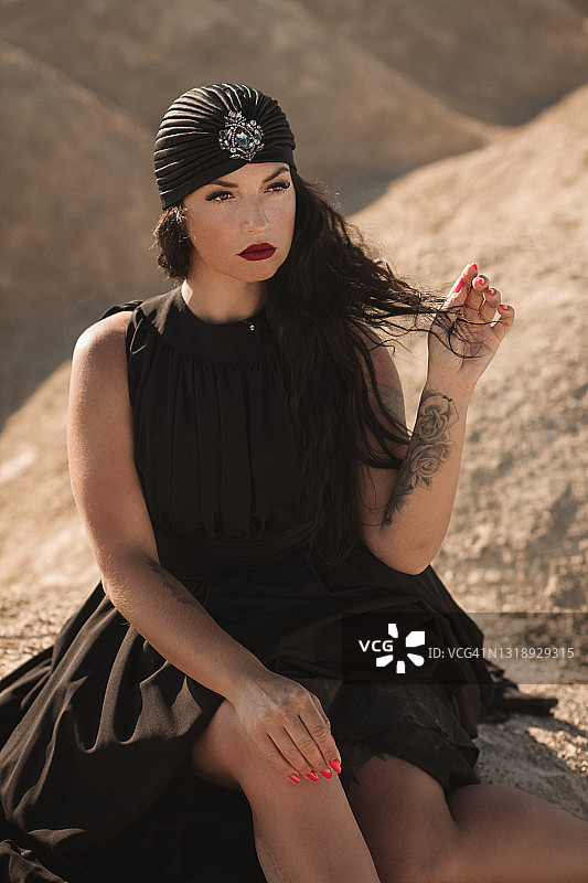 一个穿着黑衣戴着头巾的女人坐在沙漠里图片素材