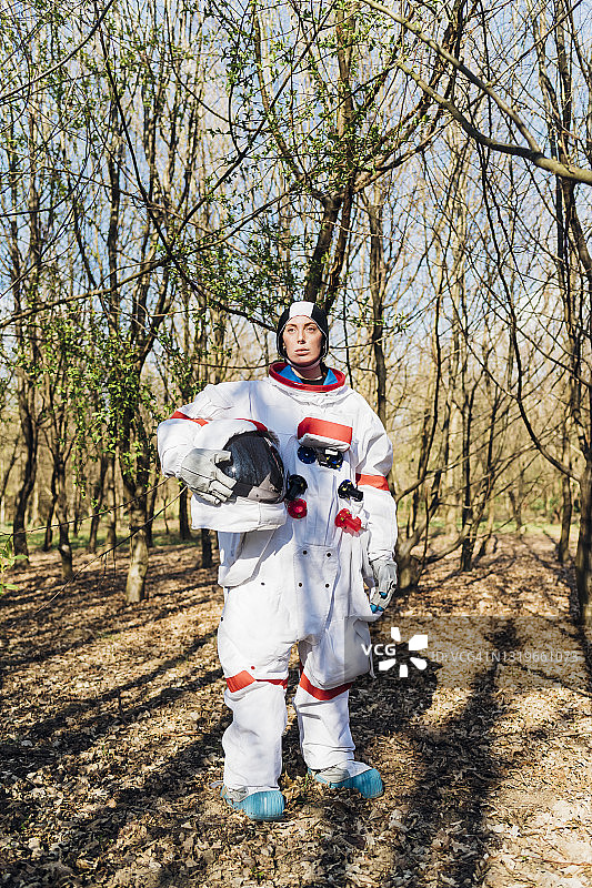 女宇航员拿着太空头盔站在森林里图片素材