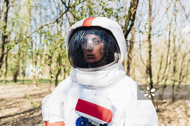 在森林里穿着宇航服和头盔的体贴的女性探险家图片素材