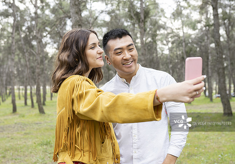 男人和美女在森林里用智能手机自拍图片素材
