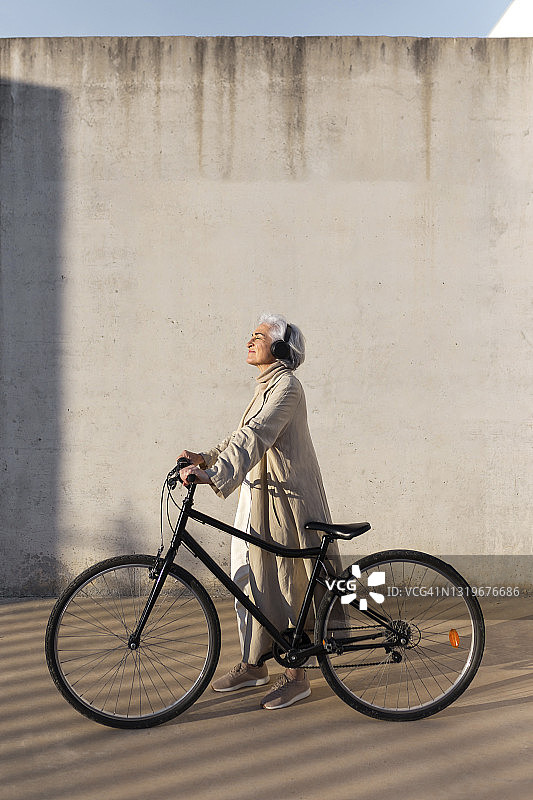 成熟的女人穿着风衣和自行车散步图片素材