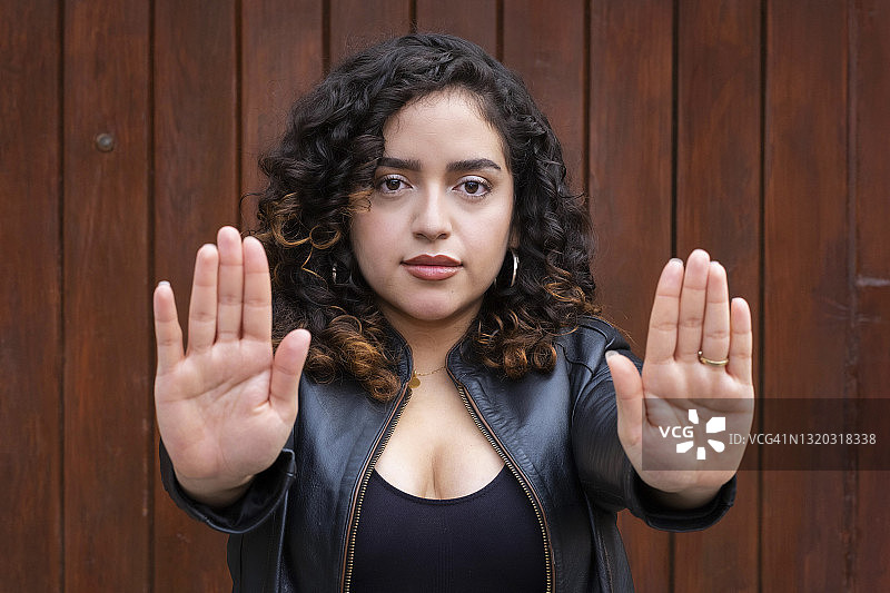 年轻的拉丁裔卷发女子看着镜头，示意停止图片素材