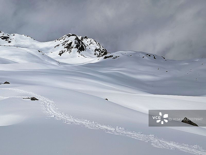 雪地上的脚印。滑雪旅游赛道上的粉末雪在瑞士山脉仙境山的景观以上的达沃斯图片素材