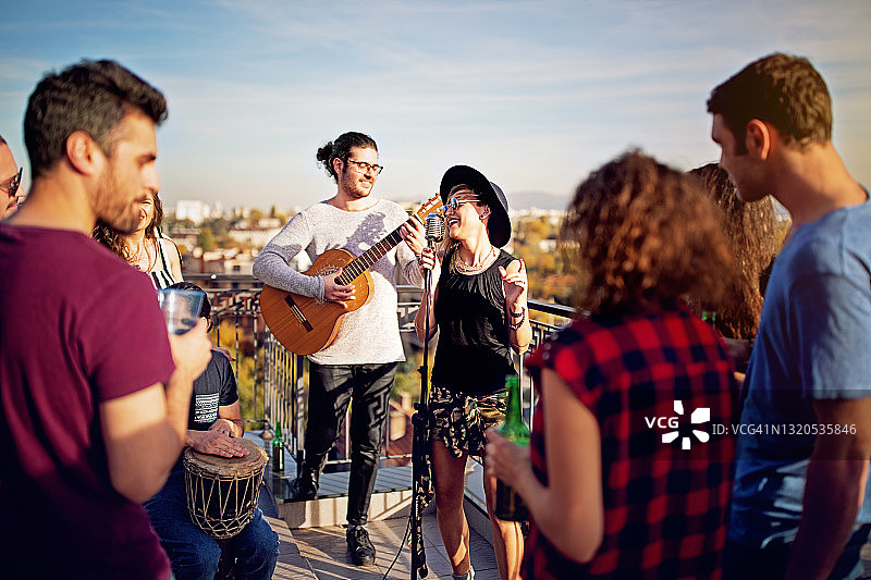 一群朋友在屋顶平台上举行音乐会庆祝图片素材