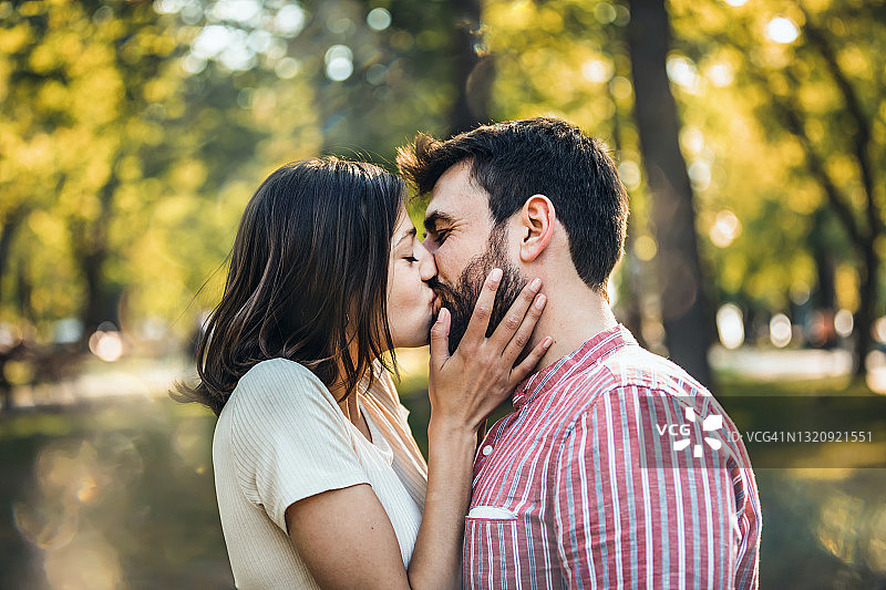 快乐的年轻情侣在公园接吻。图片素材