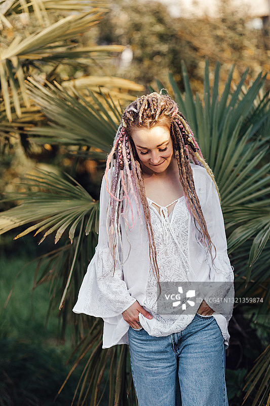 年轻的欧洲女子站在日落的棕榈树图片素材