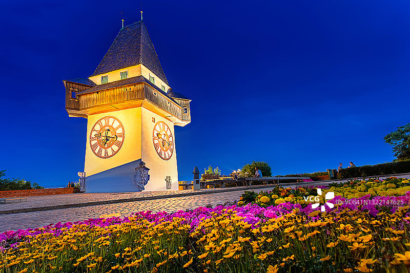 位于奥地利阿尔卑斯山脉的格拉茨市美丽而宁静的城市，坐落在市中心高山上的钟楼地标，上面有鲜花和游客青少年在晚餐后欣赏日落时间图片素材