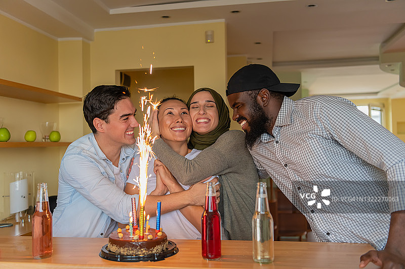 一群快乐的不同种族的朋友很高兴在家里一起度过一个生日聚会。图片素材