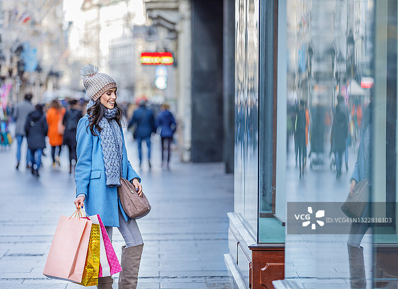 快乐女人是在城市的街道上度过一个购物日。图片素材
