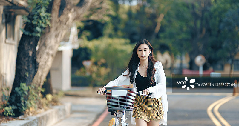 美丽的女孩租了一辆自行车在城市里旅行。图片素材