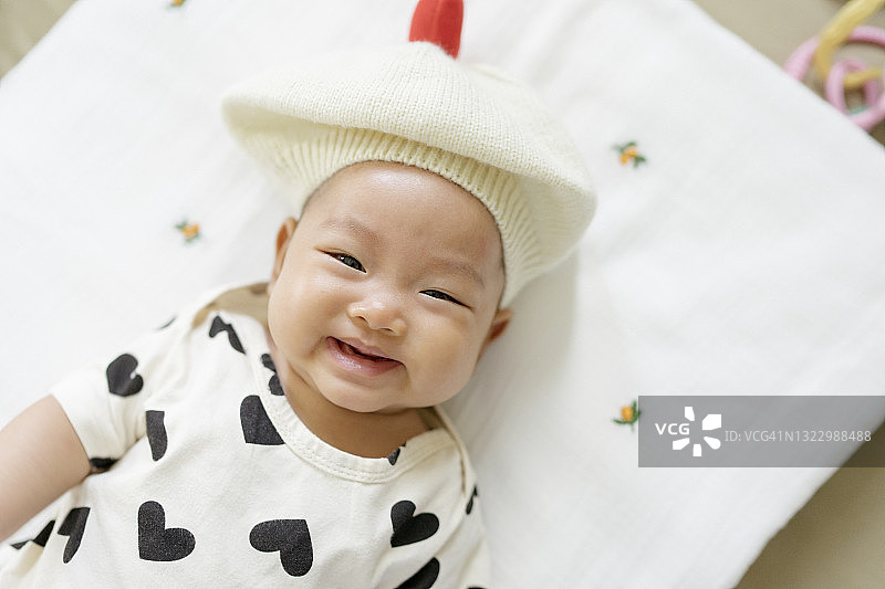 俯视图面部表情亚洲女婴(0-3个月)在舒适的床上打扮得非常可爱和清晰的背景图片素材