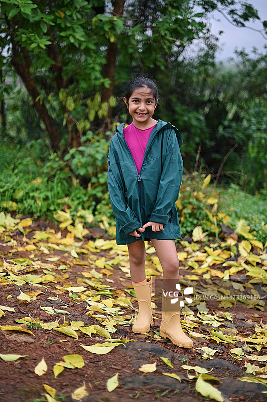 一个女孩在雨季穿着雨衣在户外的肖像图片素材