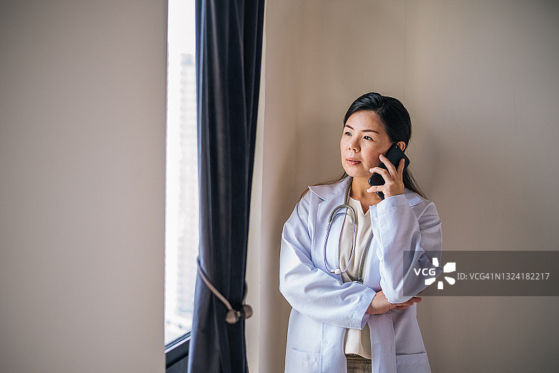 一位穿着白大褂、带听诊器、使用智能手机的亚洲女性治疗师图片素材
