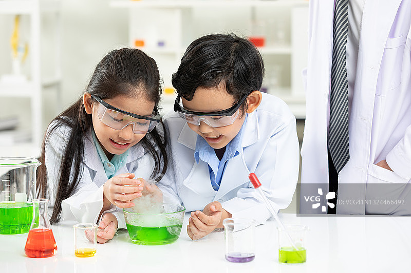 在实验教室里，孩子们在科学老师的陪同下做化学实验图片素材
