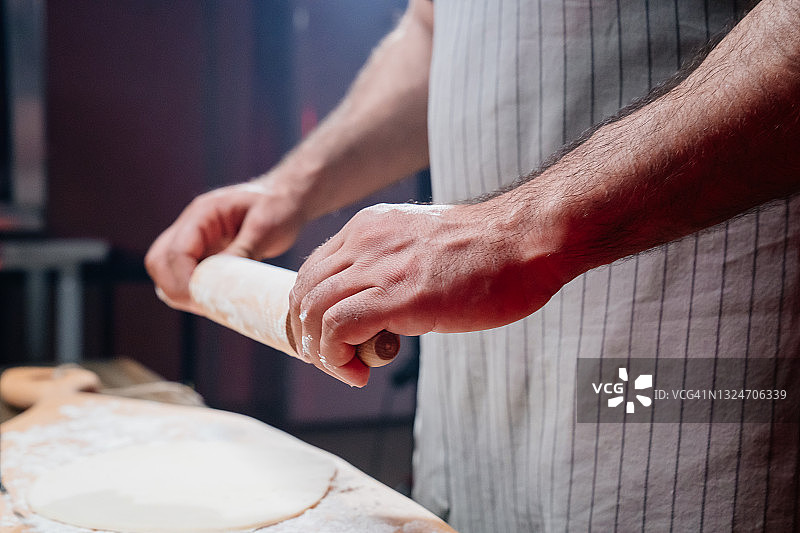 用手把面团擀成薄薄的一层。在家做披萨、面条或皮塔饼图片素材