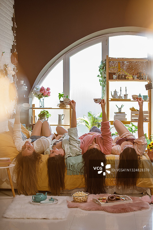 一群女性朋友躺在床上，举着茶杯图片素材