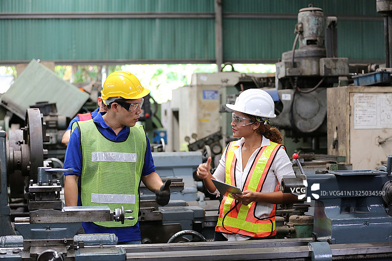 女工程师配合技术员在工厂维护检查机器零件图片素材