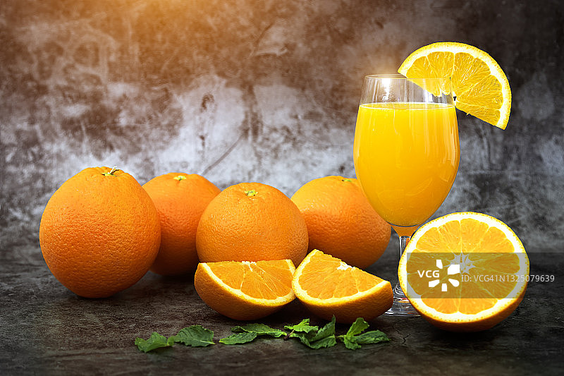 杯中的橙汁，深色背景为鲜橙图片素材