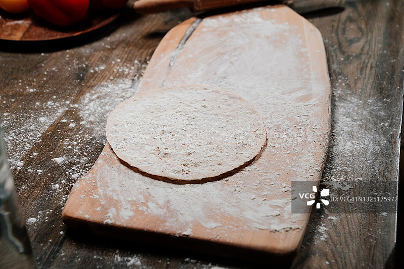 把生面团在砧板上擀成薄的玉米饼。图片素材