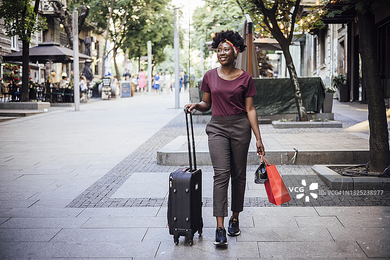 年轻的非洲妇女来到城市，带着她的行李箱图片素材