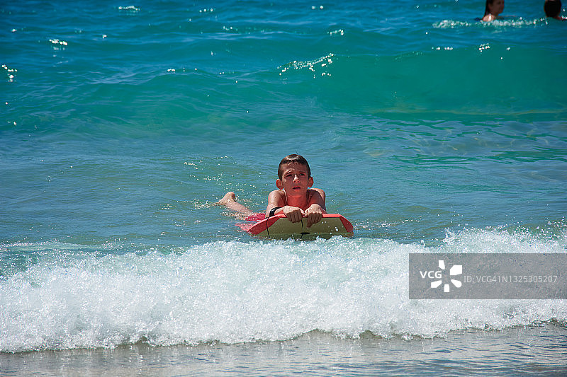 一个微笑的白人男孩在海上冲浪。图片素材
