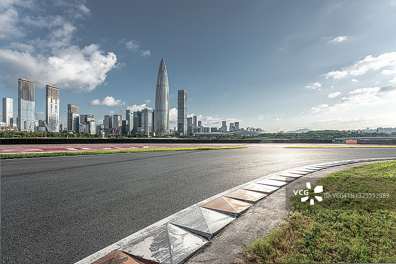 一座现代化城市的天际线和一条铺着柏油碎石的汽车轨道图片素材