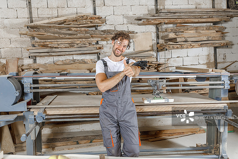 微笑的木匠在他的木工车间里感到满意。图片素材