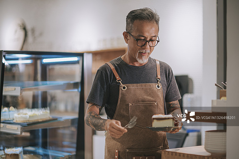 亚洲华人高级男子准备蛋糕甜点从厨房柜台服务他的客户图片素材