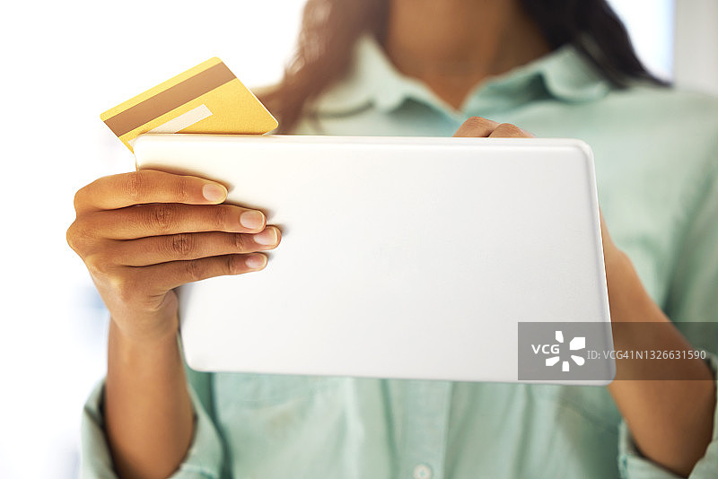 一个不知名的人用信用卡和平板电脑在家网上购物的剪影图片素材