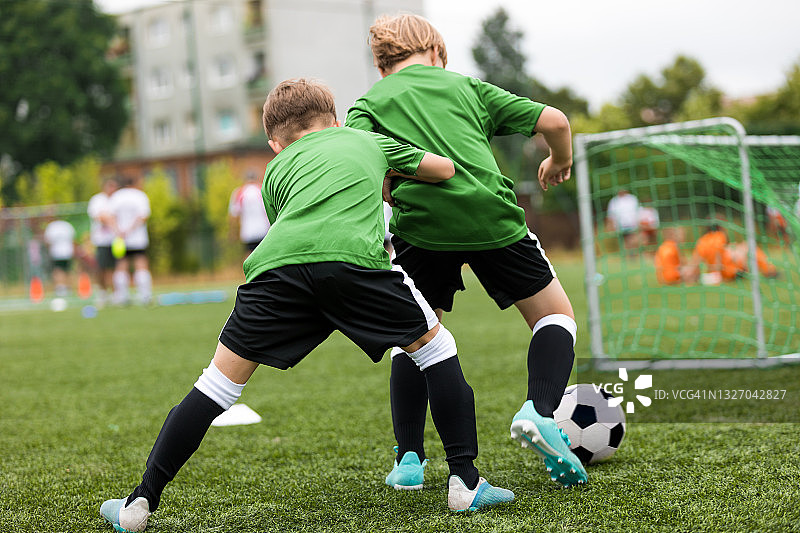 两个男孩足球比赛足球训练。快乐的孩子们在学校足球场进行体育活动。夏季学校儿童体育活动图片素材