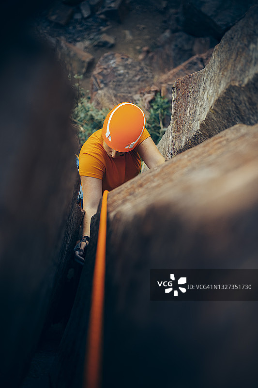 一位女性攀岩者正在陡峭岩壁上爬一条非常宽的裂缝图片素材