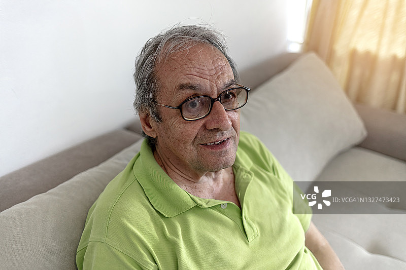 一位戴眼镜的老人在室内度过了一天。图片素材