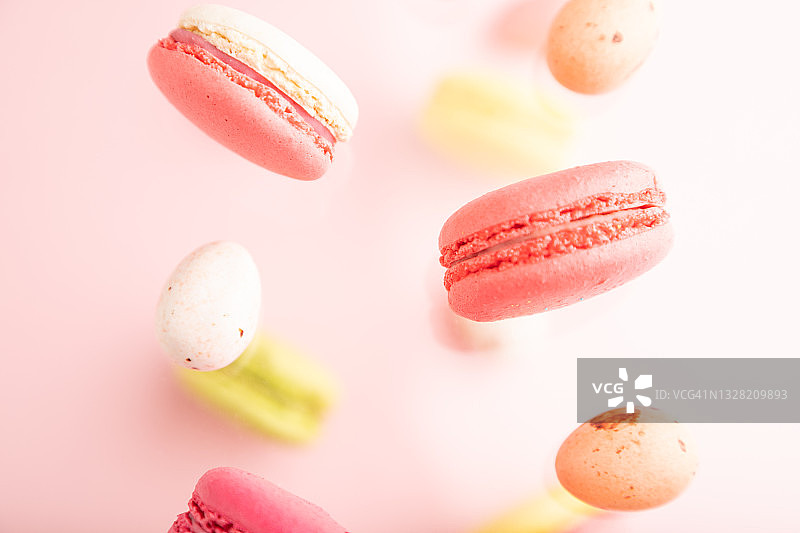 在模糊的粉红色背景下，五彩飞舞的杏仁饼干和巧克力蛋冻结在空中。俯视图，平躺，特写。早餐,早上,概念。图片素材