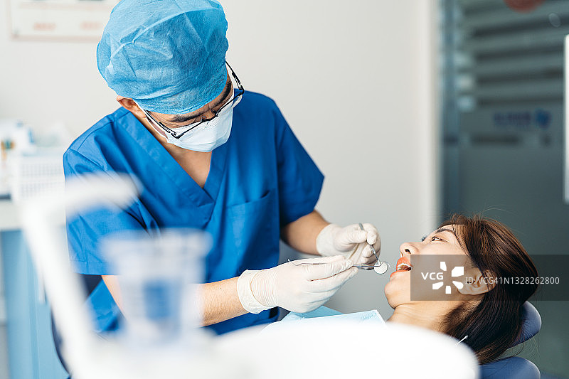 亚洲年轻迷人的女人在牙科检查期间在牙医。图片素材