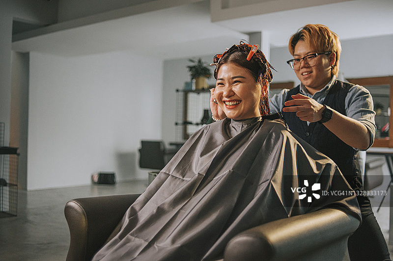 亚洲华人女发型师在发廊为顾客梳理长发图片素材