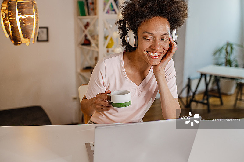 女人在家边喝咖啡边用笔记本电脑工作图片素材