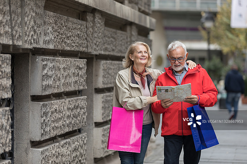 一对快乐的老年游客夫妇正在用地图探索城市。图片素材
