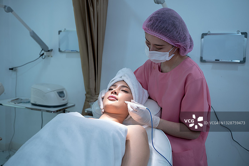 女皮肤科医生到美眉美容馆或美容诊所做面部按摩。图片素材