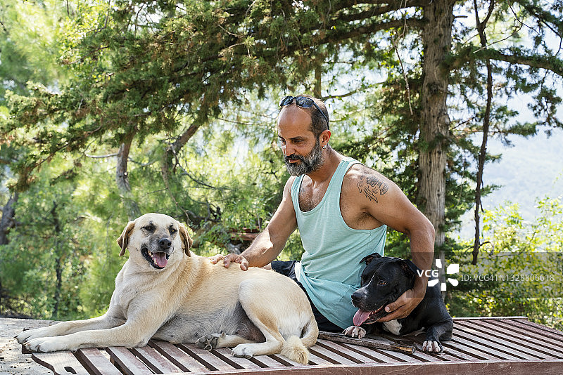 一个成熟的男人在他房子的花园里和他的狗玩耍图片素材