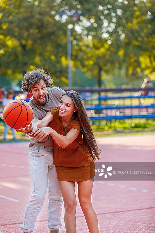一对快乐的小情侣在大自然中享受，在打篮球。图片素材