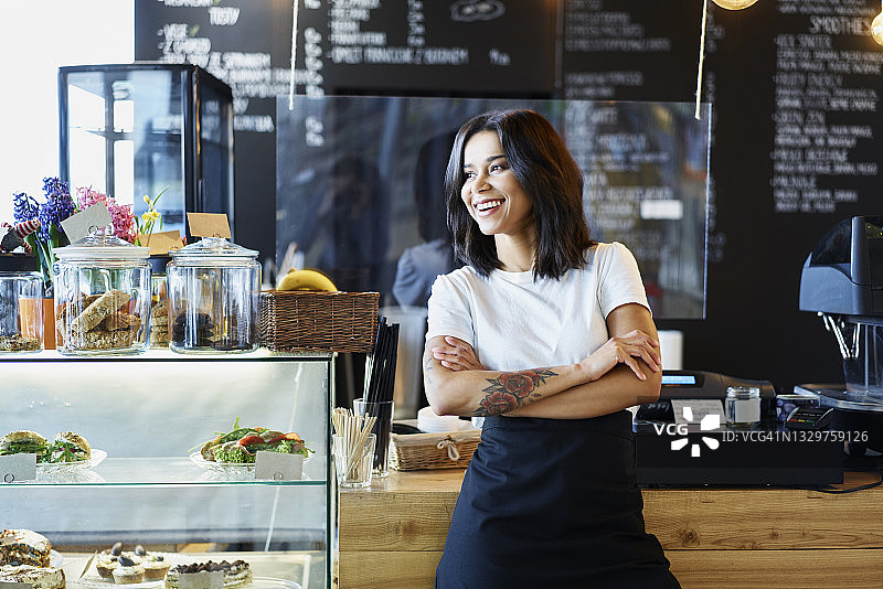 快乐的女咖啡馆老板站着。中小企业的概念。图片素材