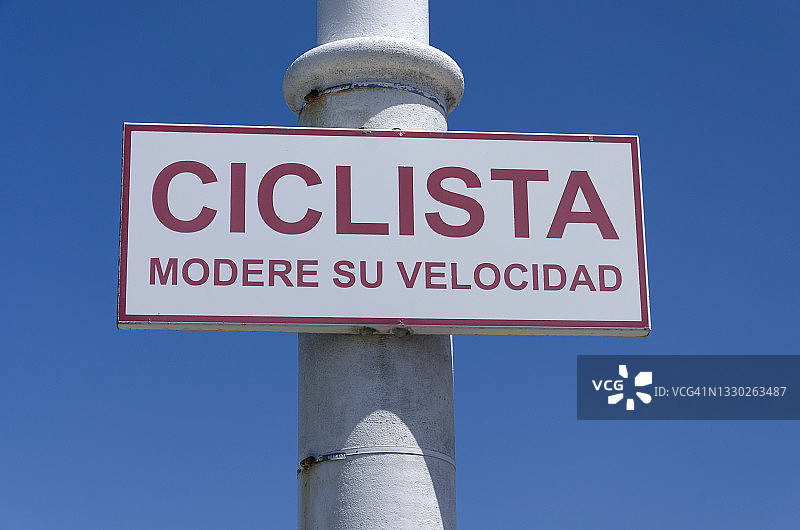 警告骑自行车者离开自行车道的标志。“CICLISTA, modere su velocidad”。骑自行车的人，用西班牙语放慢速度图片素材