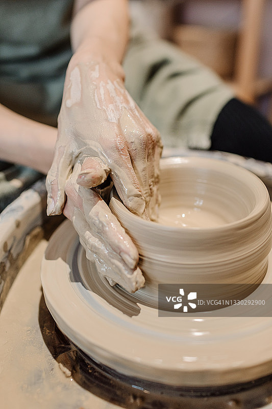 手放在陶轮后面，在做陶土陶器图片素材