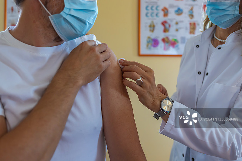 给病人肩膀打针或疫苗的成熟女性医生或护士。接种疫苗和预防流感或病毒大流行。图片素材