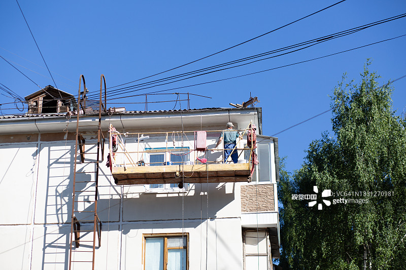 一名男性房屋油漆工在一栋住宅的前电梯上油漆。图片素材