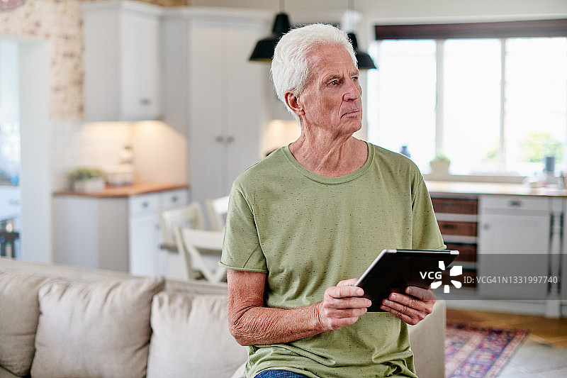 一位老人坐在家里使用数码平板电脑图片素材
