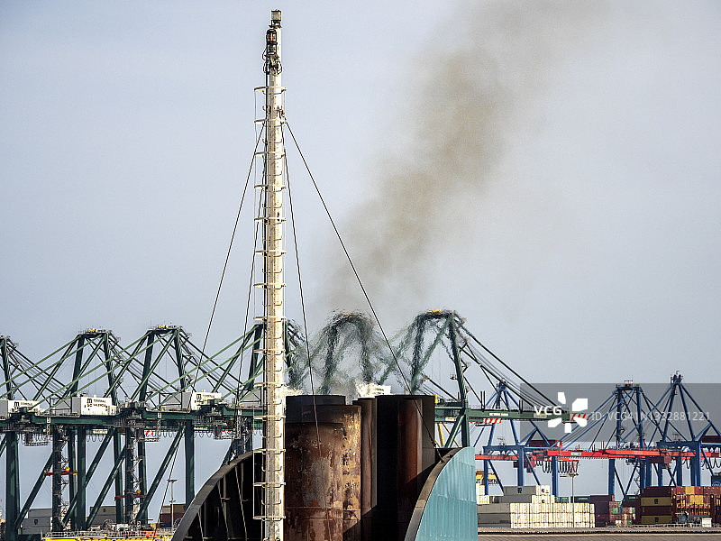 港口里一艘大型货船的烟囱产生的烟雾污染。图片素材