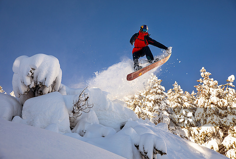 年轻的滑雪者在粉末状的一天，在一个大的跳跃的顶峰图片素材